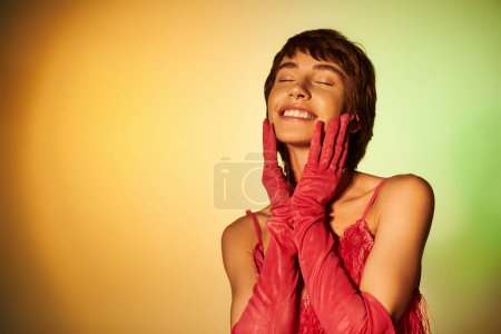 Téléchargez les photos : Une femme gracieuse en gants rouges se tient debout les yeux fermés sur une toile de fond vibrante. - en image libre de droit