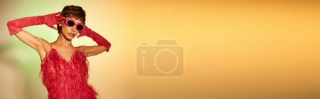 Téléchargez les photos : Femme élégante en robe rouge et lunettes de soleil frappant une pose. - en image libre de droit