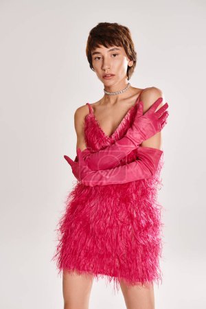 Téléchargez les photos : Une jeune femme à la mode pose dans une robe rose et des gants assortis sur un fond vibrant. - en image libre de droit