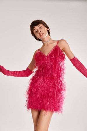 Téléchargez les photos : Stylish woman in pink dress and red gloves poses on vibrant backdrop. - en image libre de droit