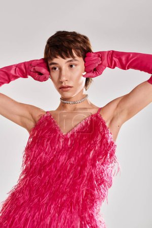 Téléchargez les photos : Femme à la mode en robe rose et gants posant sur fond vibrant. - en image libre de droit