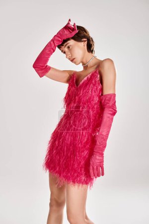 Téléchargez les photos : Jeune femme à la mode pose dans une élégante robe rose et des gants sur fond vibrant. - en image libre de droit