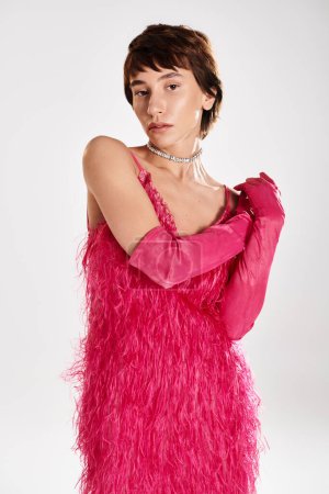 Stylish young woman strikes a pose in a vibrant pink feather dress.