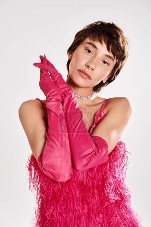 Téléchargez les photos : Une jeune femme à la mode dans une robe rose et des gants posant gracieusement. - en image libre de droit