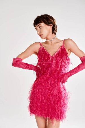 A fashionable young woman poses in an elegant pink feather dress against a vibrant backdrop.