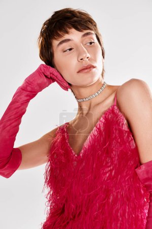 Jeune femme en robe rouge et gants posant sur fond vibrant.