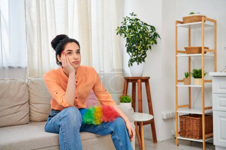 Téléchargez les photos : Une femme élégante en tenue décontractée se détend sur un canapé dans un cadre confortable salon. - en image libre de droit