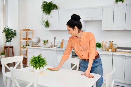 A stylish woman in casual attire meticulously wipes down a table in a home kitchen, creating a gleaming and inviting space.