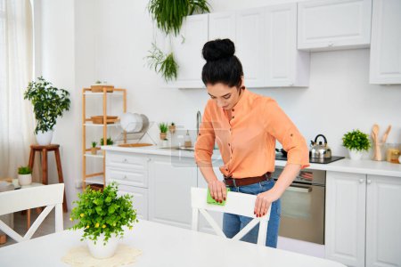 Foto de Una mujer elegante con atuendo casual se para en la cocina, cortando hábilmente un pedazo de papel con precisión y creatividad. - Imagen libre de derechos