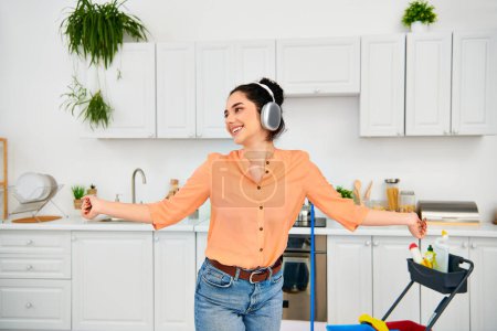 A stylish woman in headphones stands in a kitchen.