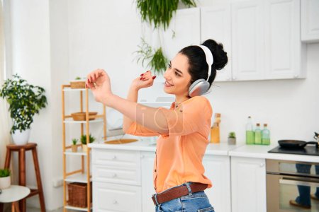 A stylish woman wearing headphones stands in a cozy kitchen, multitasking between cleaning and listening to music.