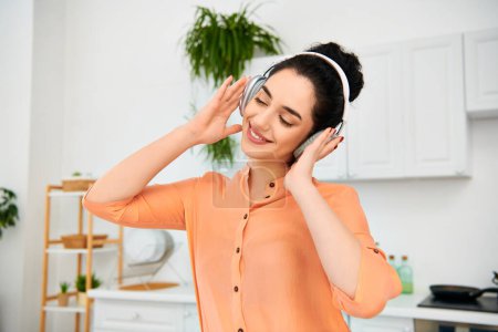 Une femme élégante dans une chemise orange écoute des écouteurs, immergée dans sa musique.