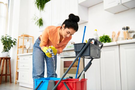 A stylish woman gracefully cleans the floor with a mop and bucket in her casual attire, adding elegance to the mundane task.
