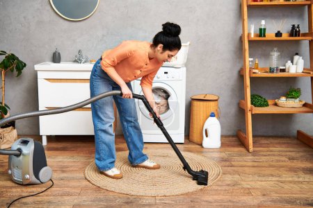 Eine stilvolle Frau in lässiger Kleidung benutzt anmutig einen Staubsauger, um den Boden ihres Hauses zu reinigen.