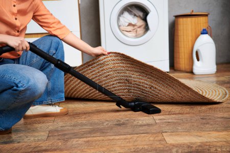 A stylish woman in casual attire diligently cleans the floor with a mop in a domestic setting.