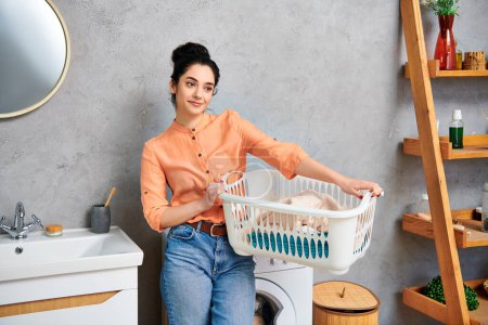 A stylish woman in casual attire holding a laundry basket standing next to a washer, preparing to do laundry.