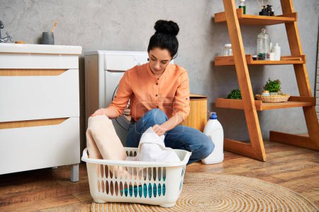 A stylish woman sits on the floor with a laundry basket in front of her, engaging in household tasks with grace and elegance.