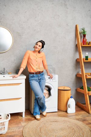 A stylish woman in casual attire stands gracefully next to a washer in a home bathroom.