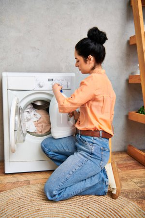 A stylish woman in casual attire sits on the floor beside a washing machine, preparing to do laundry.