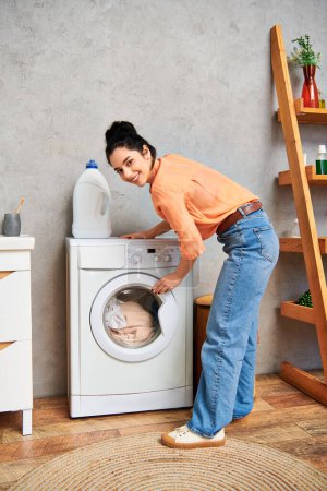 Stylowa kobieta w stroju casual stoi obok pralki, koncentruje się na czyszczeniu ubrań w domu.