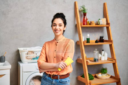 Foto de Una mujer con estilo y atuendo casual se para junto a una lavadora en un baño, enfocada en hacer la colada. - Imagen libre de derechos