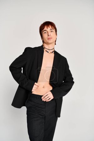 Stylish young man in a suit striking poses against a grey backdrop in a studio setting.