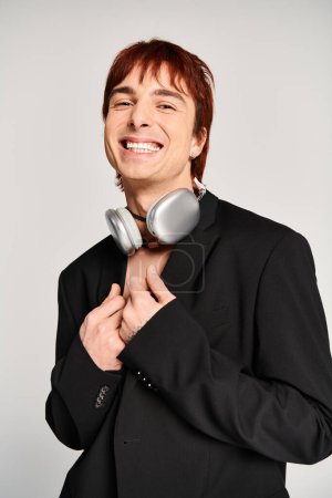 Ein stilvoller junger Mann im schwarzen Anzug posiert mit Kopfhörern.