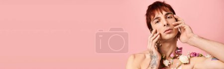 Photo for A young man with tattoos poses with flowers in a studio against a pink background. - Royalty Free Image