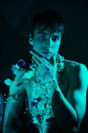 Ein junger Mann posiert, ohne Hemd und mit zarten Blumen geschmückt