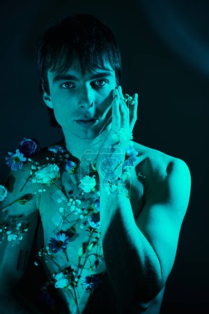 Foto de Un joven con flores en el pecho sostiene sus manos a la cara en un gesto contemplativo. - Imagen libre de derechos