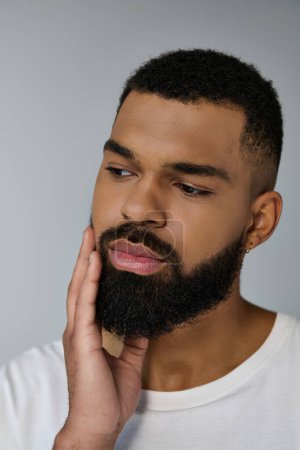 Close up of a appelaing young man grooming his beard.