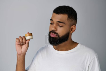 Un homme à la barbe tient délicatement la crème.
