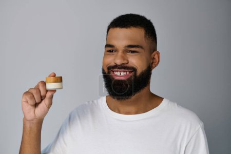 Photo for Handsome man with a beard holding cream. - Royalty Free Image