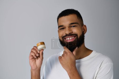A bearded man holding a jar of cream.