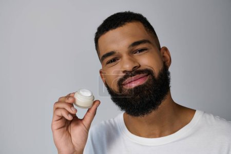 Handsome man with beard holding jar of cream.