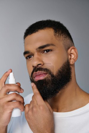 African american young man with a beard applying locion on his face.