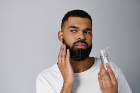 African american stylish man with a beard applying locion on his face.