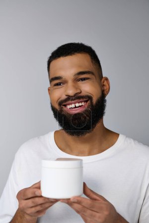Afro-Américain bel homme avec une barbe tenant un pot de crème.