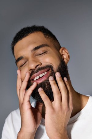 Smiling man with beard, hands on face.