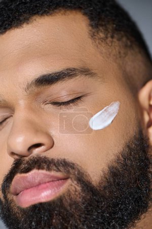 Foto de Close-up of a young man with a beard applying cream. - Imagen libre de derechos