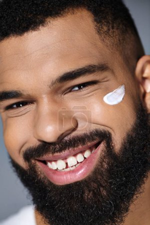 Hombre de moda afroamericano con una barba mostrando crema blanca en su cara.
