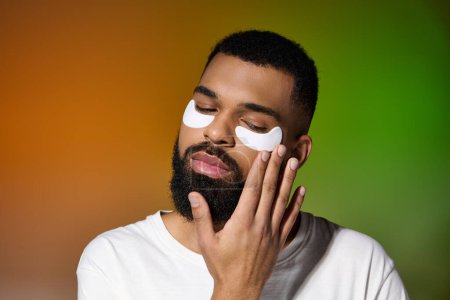 Un beau jeune homme avec deux patchs sur le visage pendant sa routine de soins de la peau.