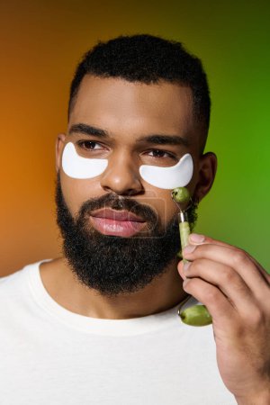 Handsome young man with eye patches on his face, following a skin care routine.