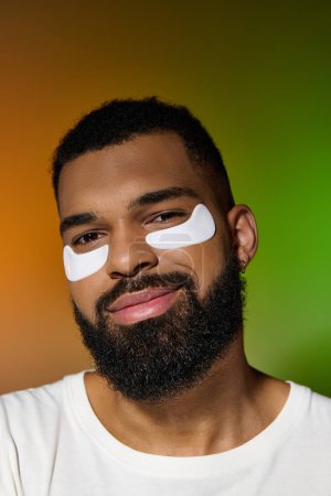 Photo for Handsome man with eye patches on his face, beauty routine underway. - Royalty Free Image