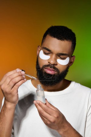 Handsome young man applying eye patches for his skincare routine.