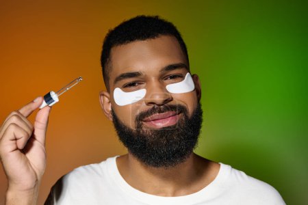 African american young man using eye patches and serum.