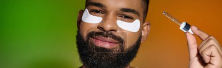 African american bearded man using eye patches and serum.