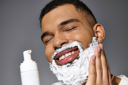 Ein junger Mann inmitten seiner Hautpflege-Routine, der sein Gesicht mit einer Schicht Schaum rasiert.