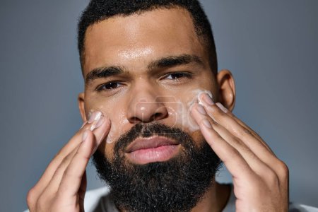 A bearded man gently shaves his face in his skin care routine.