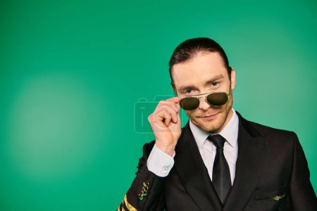 Téléchargez les photos : Un pilote mâle dappeur en uniforme noir frappe une pose sur fond vert. - en image libre de droit
